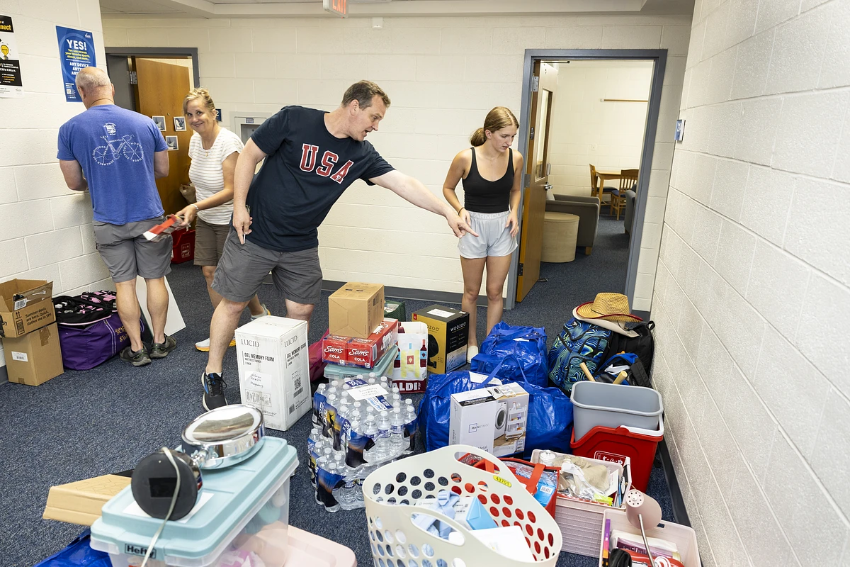 Students and their family members and supporters move boxes and things into a residence hall.